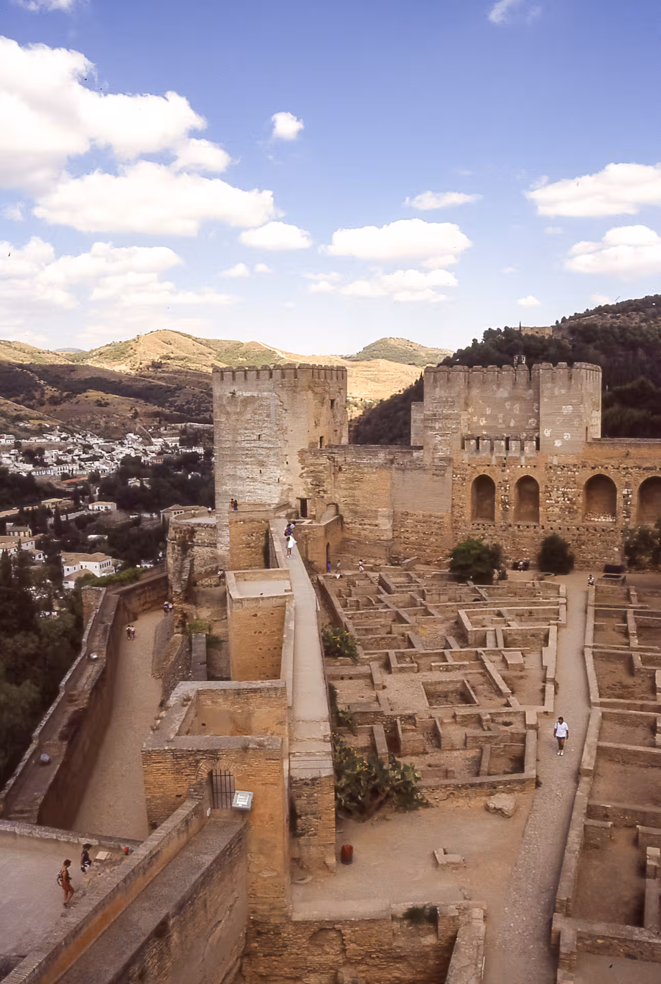 Aerial view of Alhambra's ancient fortress walls and towers with panoramic Sierra Nevada backdrop.