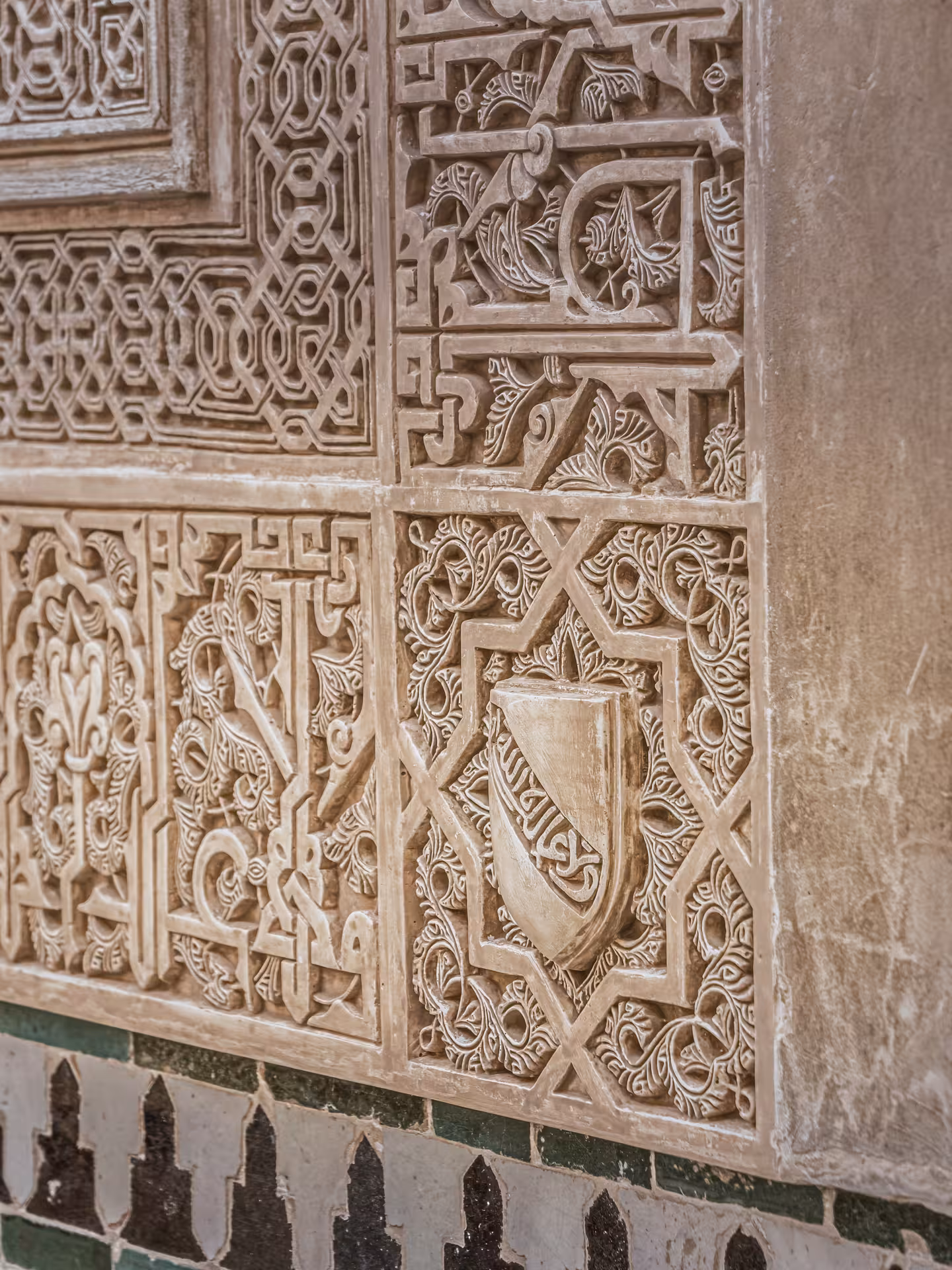 Intricate Islamic carvings on a wall in the Nasrid Palaces of the Alhambra, showcasing historic Moorish artistry.