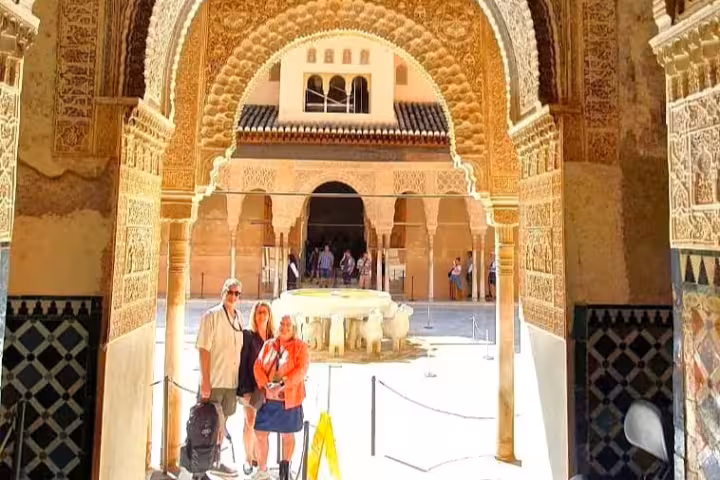Guests beneath ornate Moorish arch at Alhambra Nasrid Palaces courtyard, Granada private walking tour