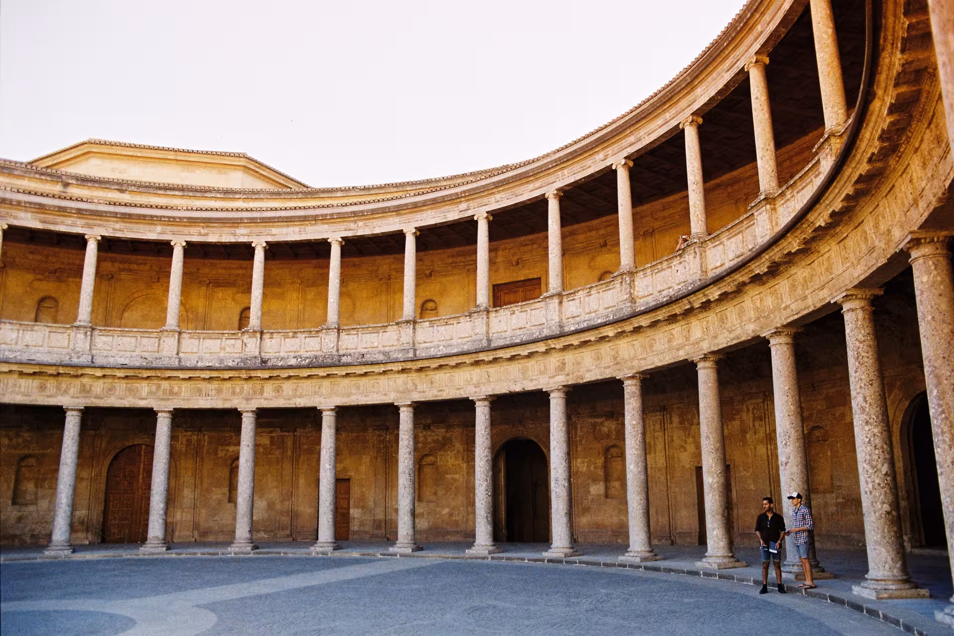 Circular courtyard of the Alhambra's Palace of Charles V, featuring majestic stone columns in Granada.