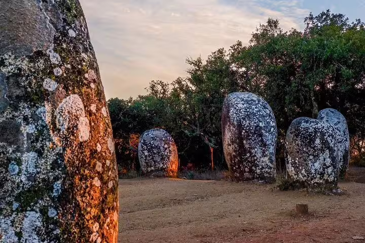 Ancient megalithic stones at Almendres Cromlech, Évora, under a scenic sky, part of a full-day tour from Lisbon.