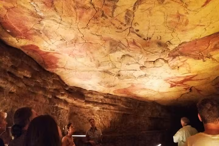 Visitors admire prehistoric cave paintings at Altamira Museum, showcasing ancient artistry near Santillana del Mar.