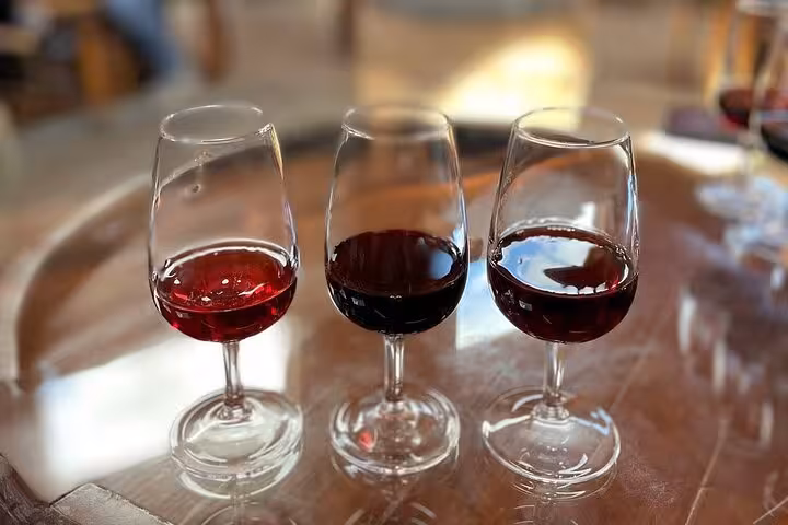 Three glasses of Port wine tasting flight on wooden barrel during Alto Douro wine region guided cultural tour