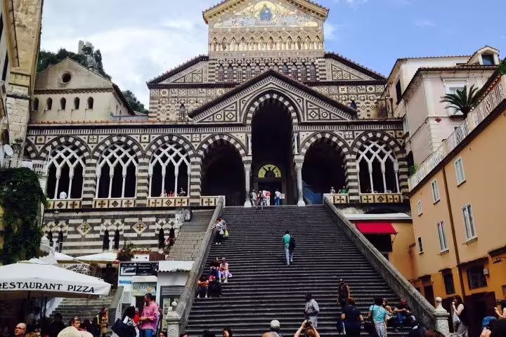 Tourists climbing the grand staircase to Amalfi Cathedral, a highlight stop on the Ravello Amalfi Positano coast day tour