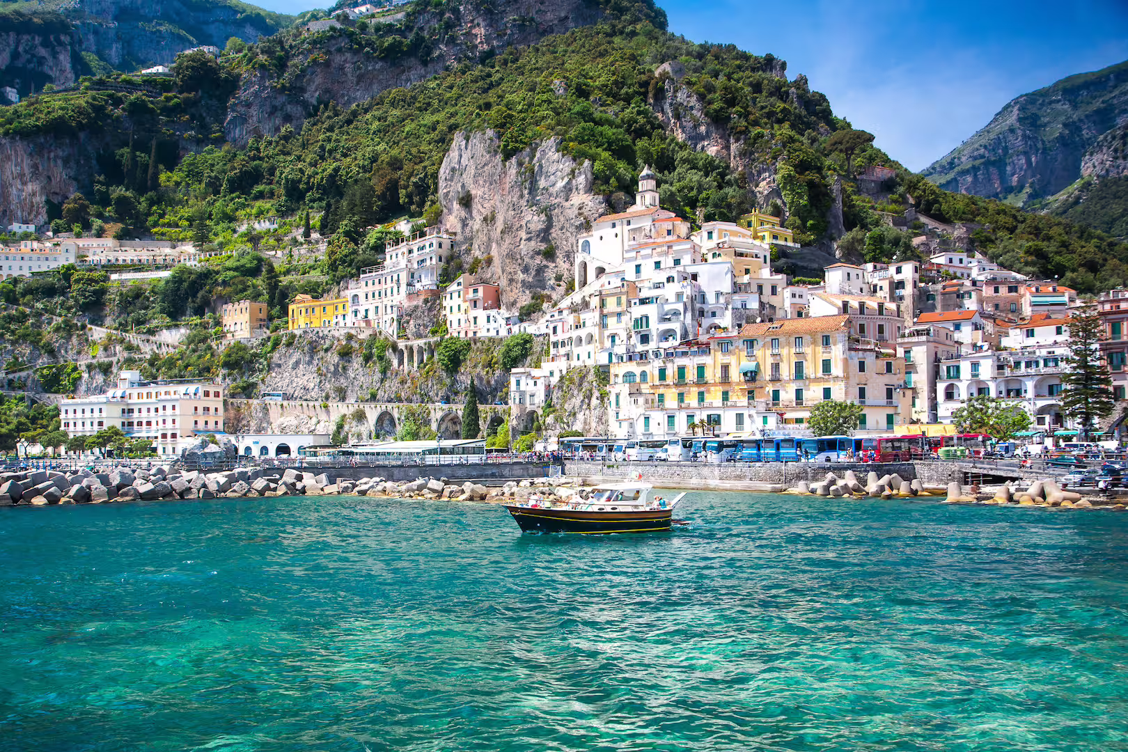 Charming Amalfi town with colorful hillside buildings and boat on turquoise waters, perfect for tours.
