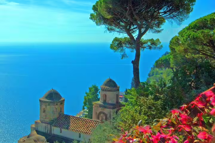 Scenic view of Amalfi Coast with church domes, lush greenery, and turquoise Mediterranean Sea from Ravello