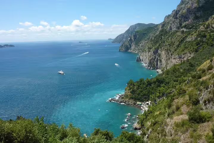 Panoramic Amalfi Coast cliffs and turquoise sea with boats, coastal views on Naples to Amalfi day trip