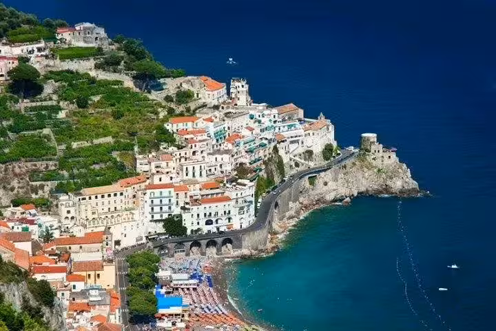 Clifftop view of Amalfi Coast village with terraced hills, coastal road and turquoise bay on a private shore excursion tour