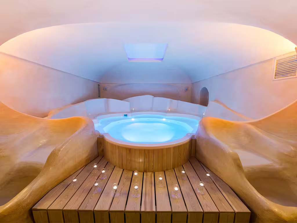 Intimate Amalfi Coast spa with candlelit hydrotherapy hot tub, curved walls and relaxing wellness atmosphere for couples