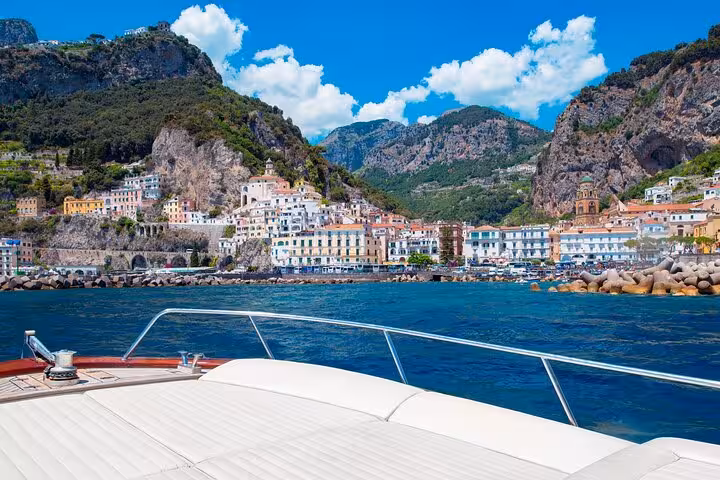 Picturesque view of Amalfi coast from a Gozzo boat tour, showcasing vibrant buildings and dramatic cliffs.