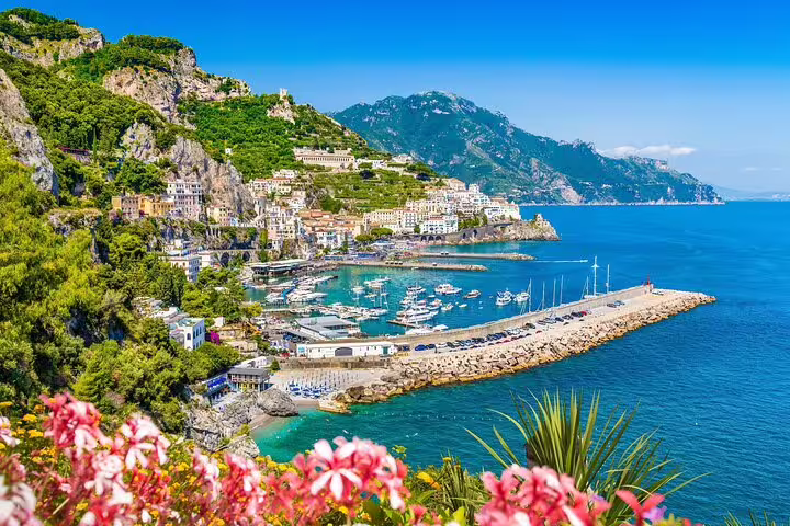 Amalfi Coast town with colorful cliffside buildings, marina with boats, and turquoise Mediterranean sea
