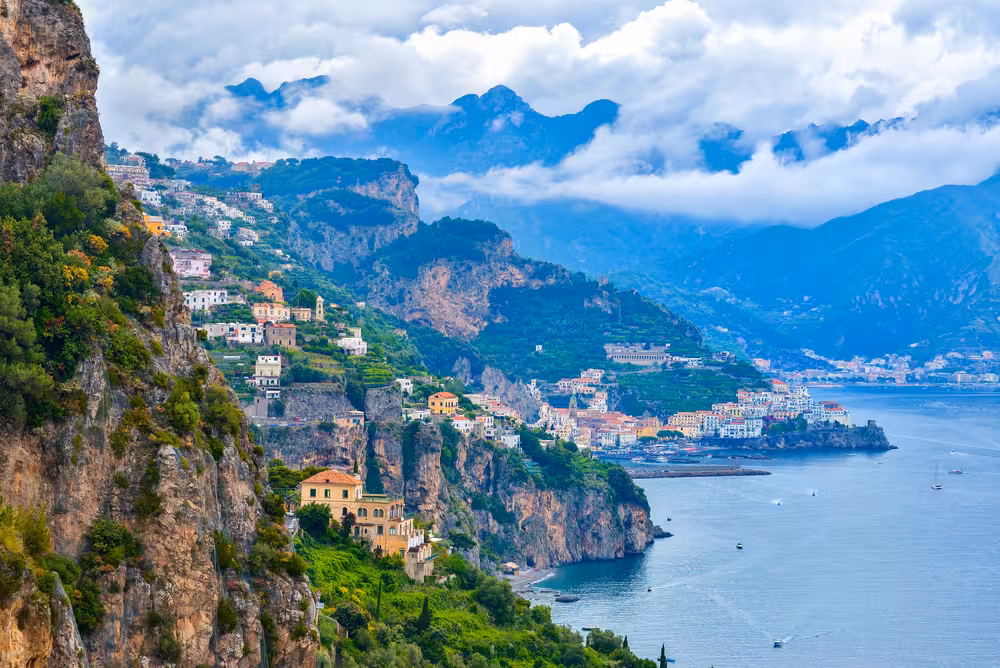 Breathtaking view of Amalfi Coast's cliffside villages with lush greenery and turquoise sea from a Naples day trip.