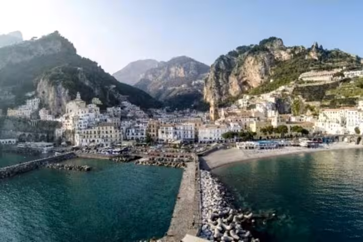 Panoramic view of Amalfi town and harbor with cliffs and turquoise sea, coastal stop on shared tour from Ravello to Positano
