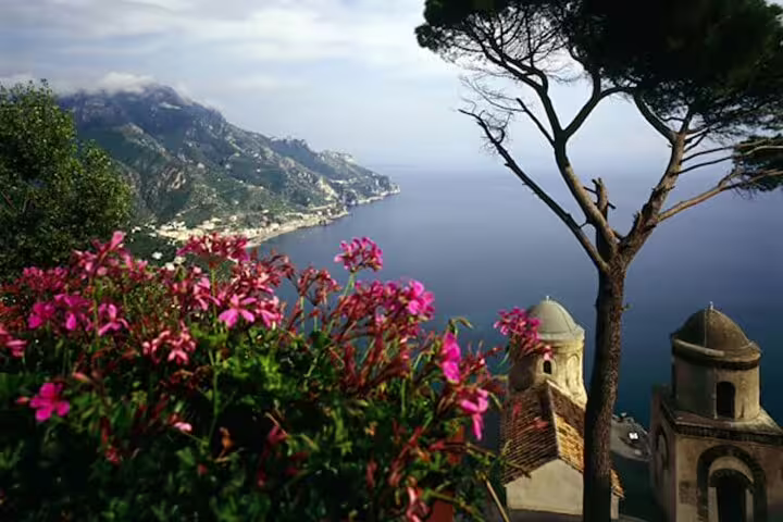 Panoramic view of Amalfi Coast with pink oleander flowers, church domes, and Mediterranean sea from Ravello