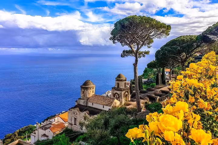 View of the Amalfi Coast from Positano with vibrant flowers, historic architecture, and the azure Mediterranean Sea.