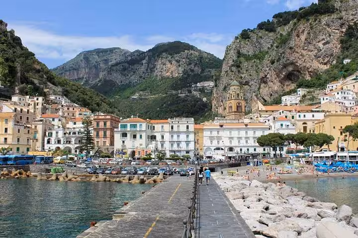 Discover the picturesque Amalfi waterfront with vibrant buildings and dramatic cliffs, perfect for your full-day adventure.