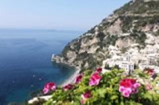 Scenic Amalfi Coast cliffside with bright pink flowers, secluded beach and blue Tyrrhenian Sea on a private shared tour