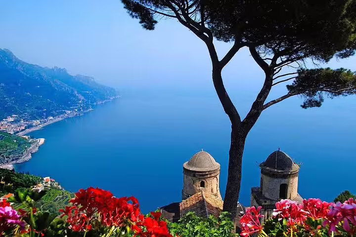 Panoramic view of Amalfi Coast from Ravello with red flowers, church domes, and blue Mediterranean Sea
