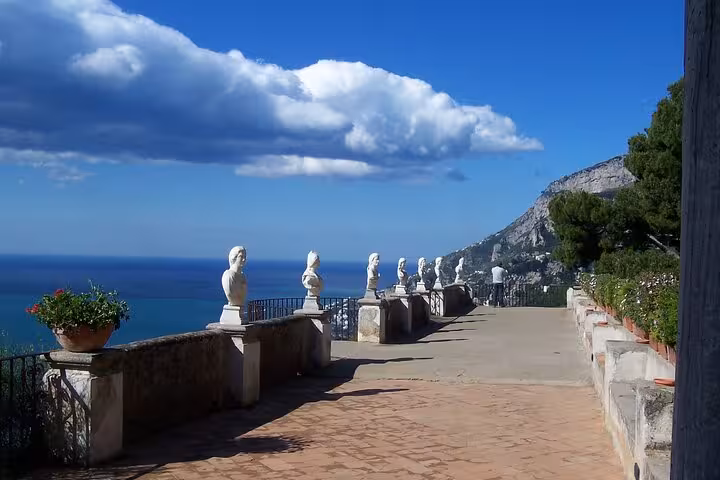Scenic terrace with classical statues overlooking the Amalfi Coast's blue sea in Ravello, Italy.