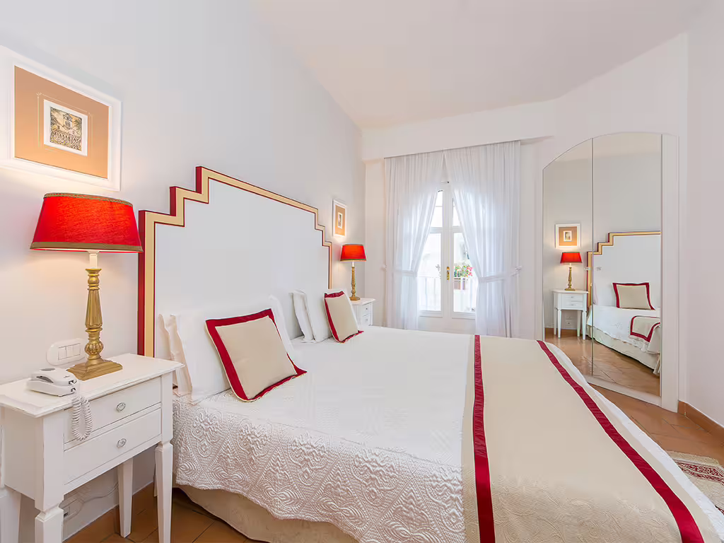 Elegant Amalfi Coast double room with red accents, balcony view and cozy lighting, perfect for a romantic spa getaway
