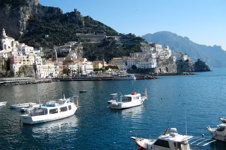 Charming coastal view of Amalfi with colorful buildings and boats on a serene blue sea, perfect for exploring.