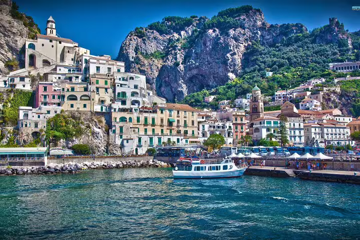 Amalfi town waterfront with colorful hillside buildings and ferry boat on VIP Amalfi Coast small group tour