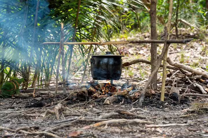 Traditional Amazonian outdoor cooking setup with a pot over a fire, illustrating jungle survival techniques.