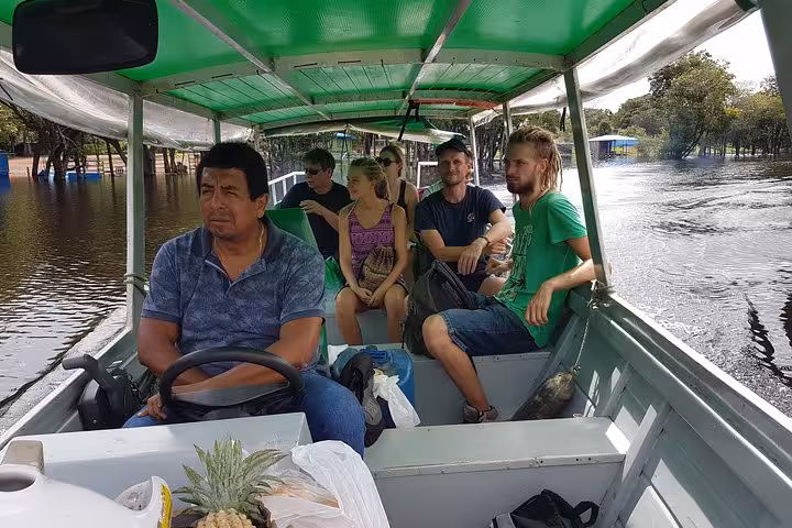 Travelers ride a covered river boat with local guide on a 5-day Amazon jungle adventure tour in Peru