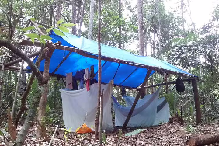 Rustic jungle survival camp shelter with blue tarp and hammocks deep in the Amazon rainforest Manaus
