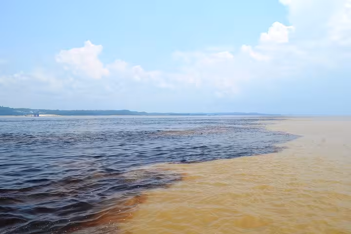 Meeting of waters on Amazon Negro River half-day expedition tour, where dark and sandy currents flow side by side