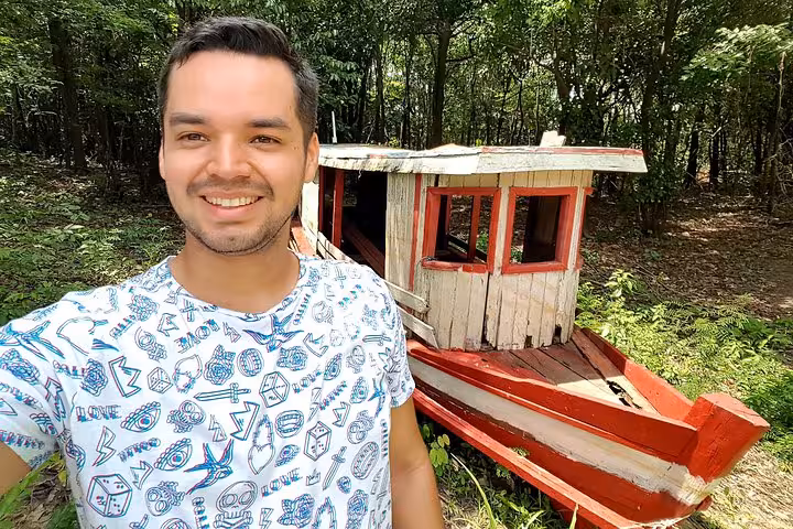 Smiling traveler selfie by a rustic wooden boat in the Amazon rainforest, part of a 4-hour trekking tour