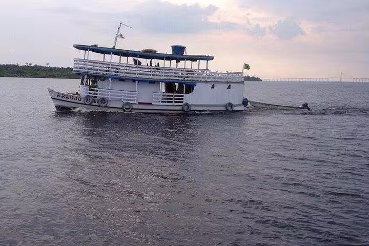 Small Amazon River boat cruising near Manaus at dusk, Brazil, on a scenic rainforest river adventure tour