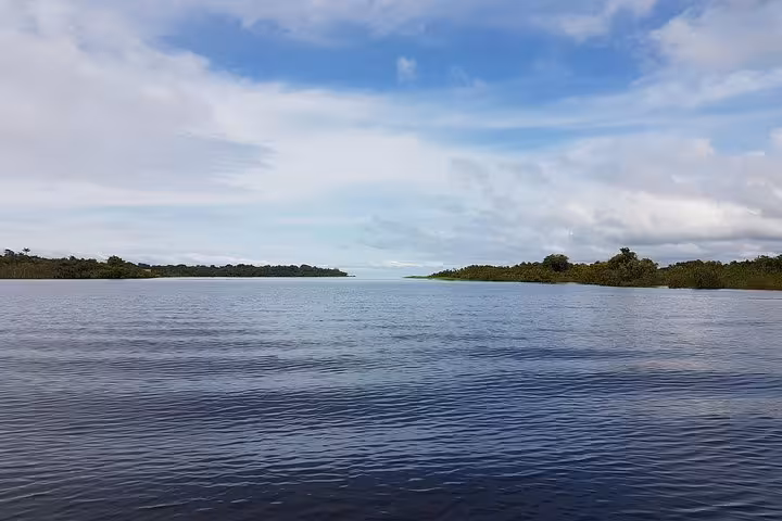 Wide Amazon River view with calm waters and rainforest horizon, part of Good Morning Amazon 1-night jungle tour