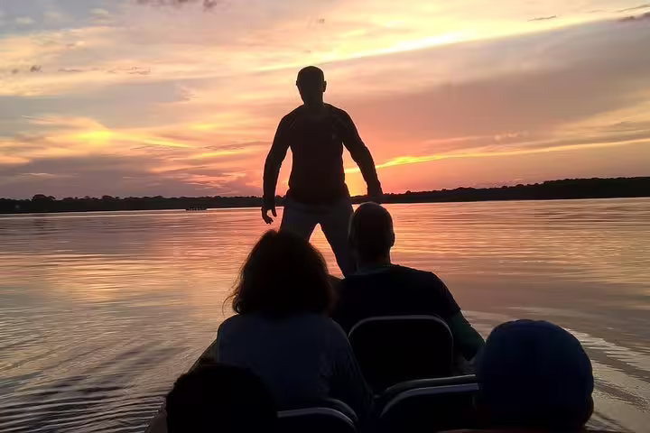 Tourists on a boat watching a stunning Amazon River sunset during a 4-day jungle survival tour from Manaus