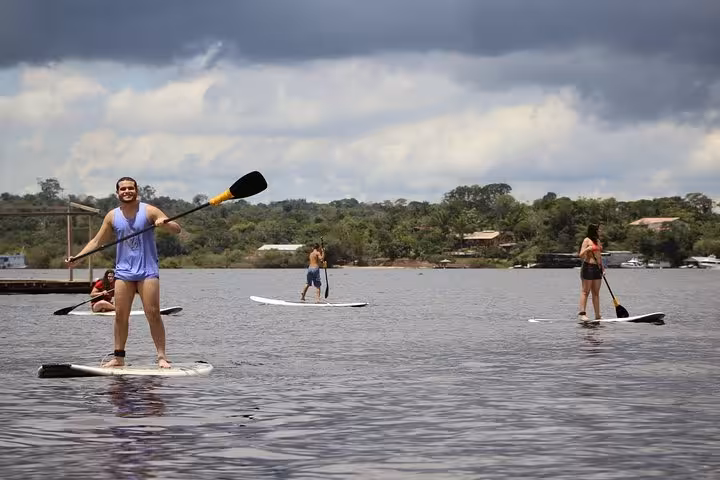 Travelers stand up paddleboarding on the Amazon River, small group SUP tour under dramatic clouds