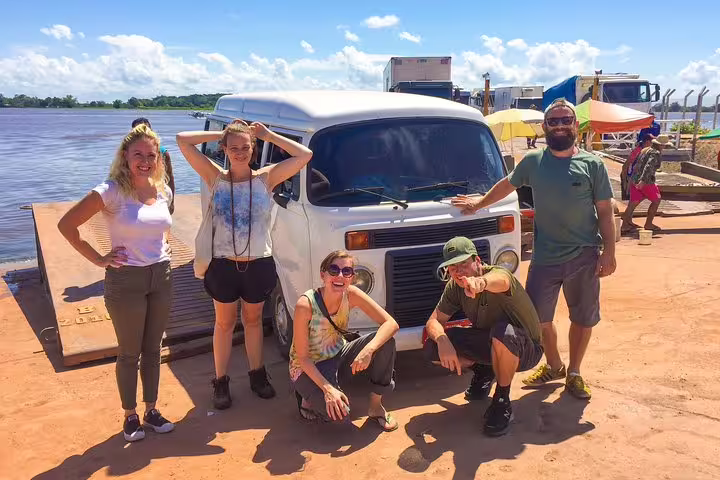 Group of travelers posing by a van near a river, ready for the Amazon Survival Tour 3D/2N journey.