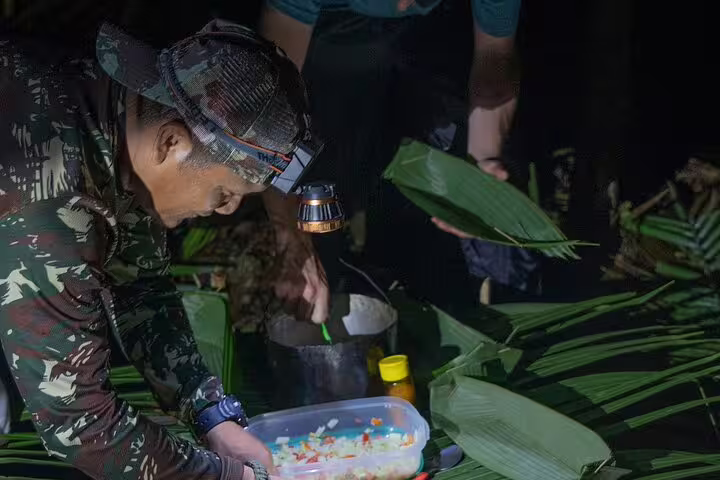 Tourist experiencing traditional Amazonian cooking at night, using fresh ingredients and banana leaves.