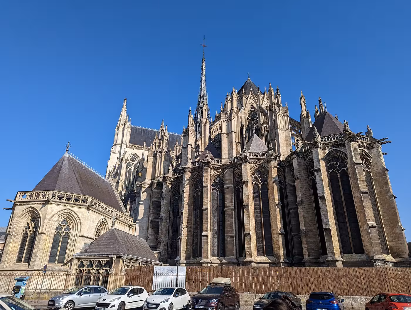 Gothic flying buttresses and spire of Amiens Cathedral viewed from outside on a clear blue sky day
