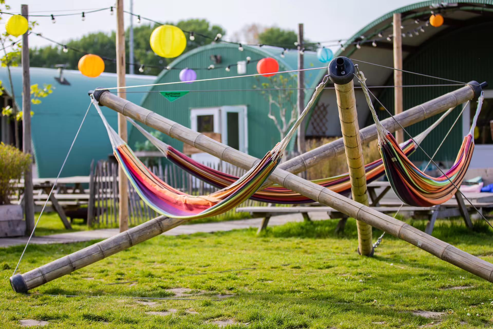 Relax area at Amsterdam archery venue with colorful hammocks, picnic benches, and string lights outdoors