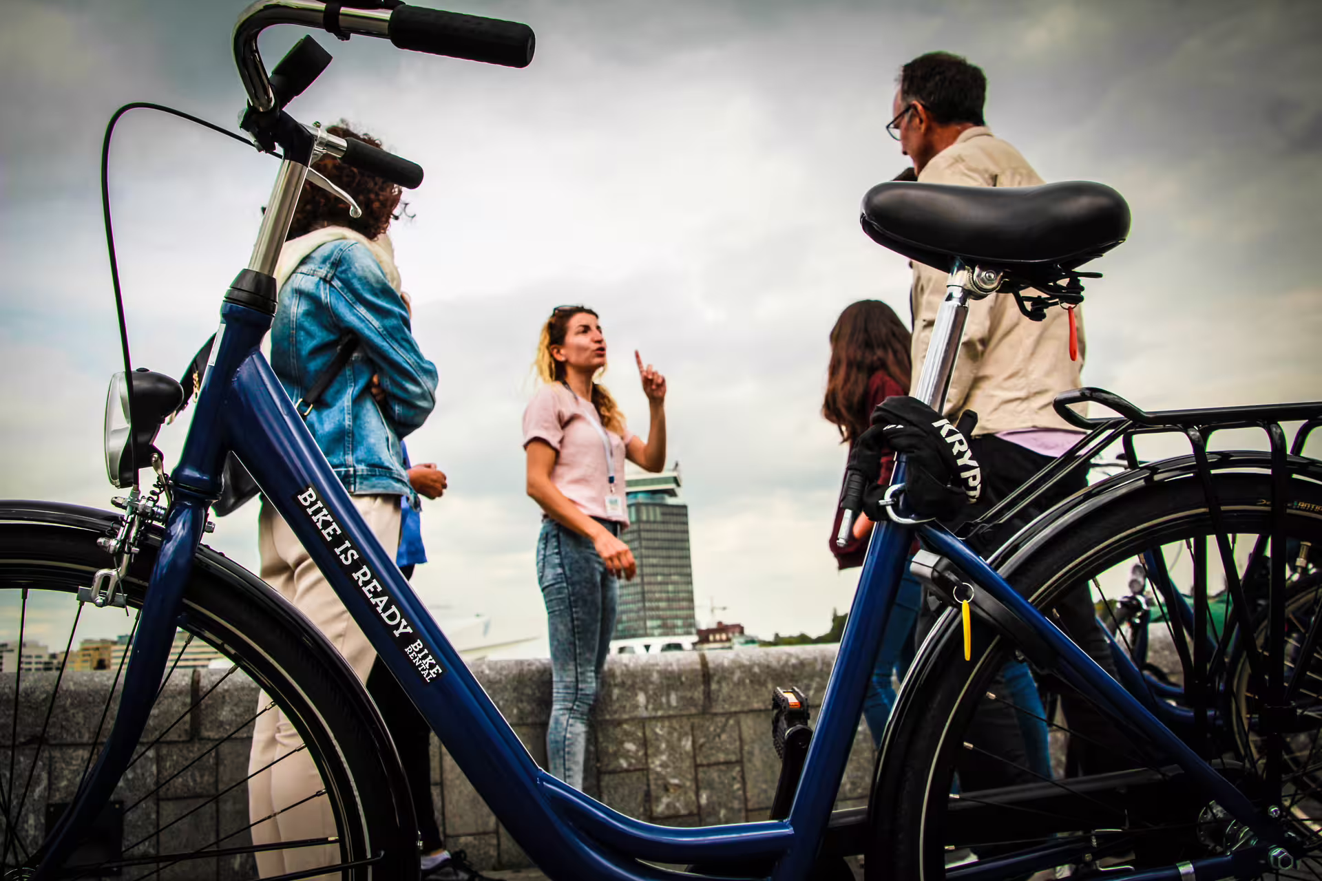 Cyclists enjoy a guided bike tour in Amsterdam with canal views, featuring cheese tasting and drinks, highlighting local culture.