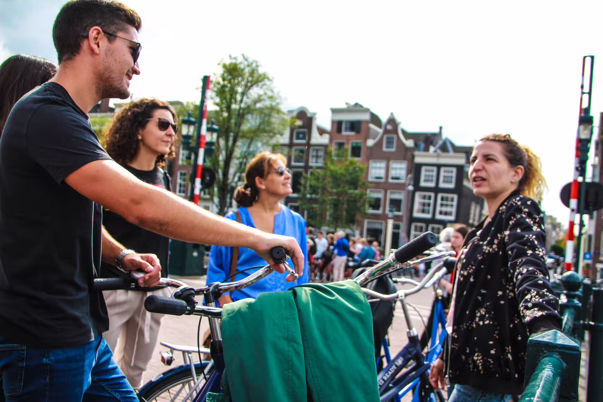 Group of tourists enjoying an Amsterdam bike tour with canal cruise, surrounded by historic buildings and vibrant city life.