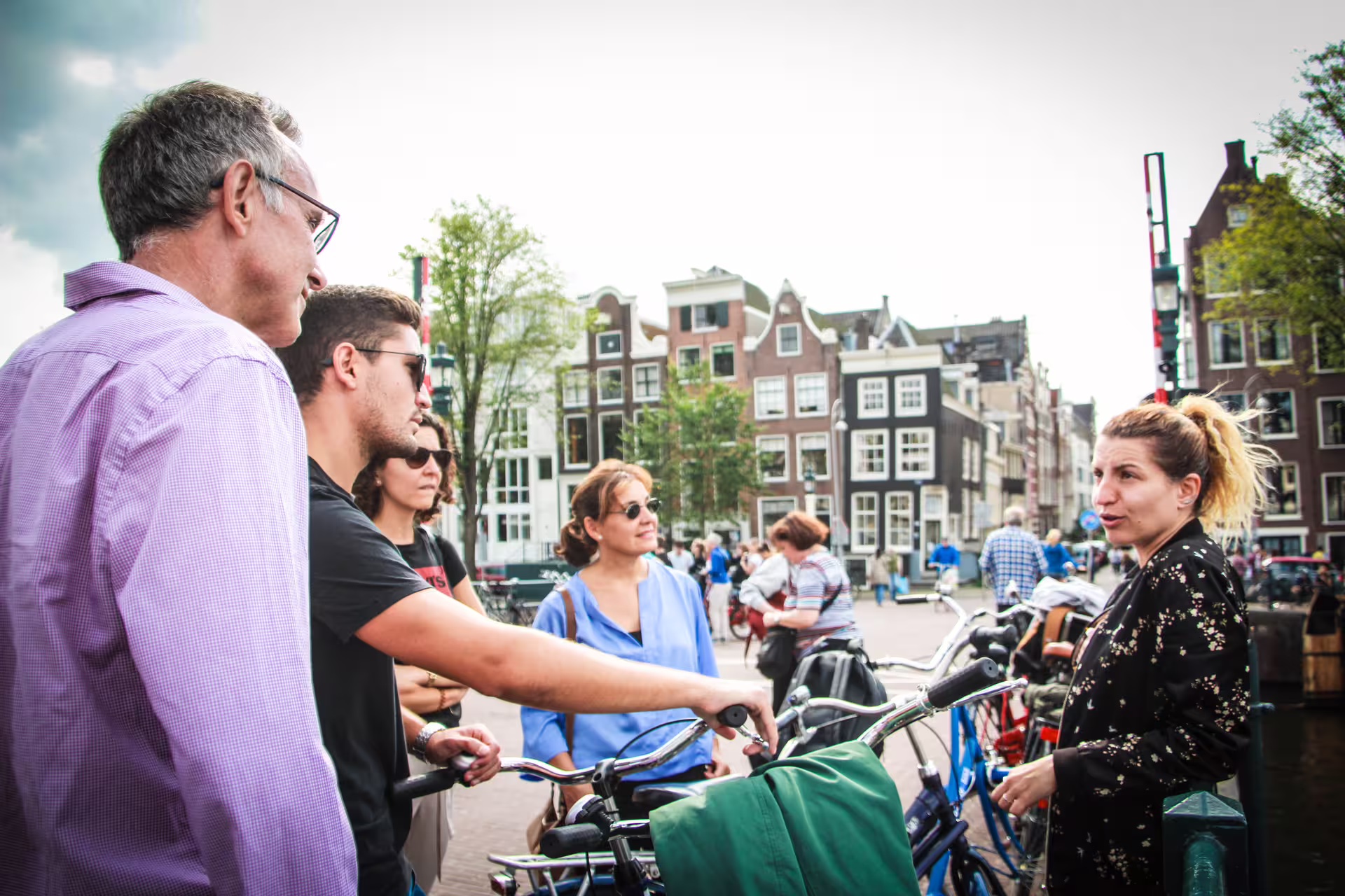 Tour guide leading a small group on bikes through scenic Amsterdam canals, showcasing the city's iconic architecture.
