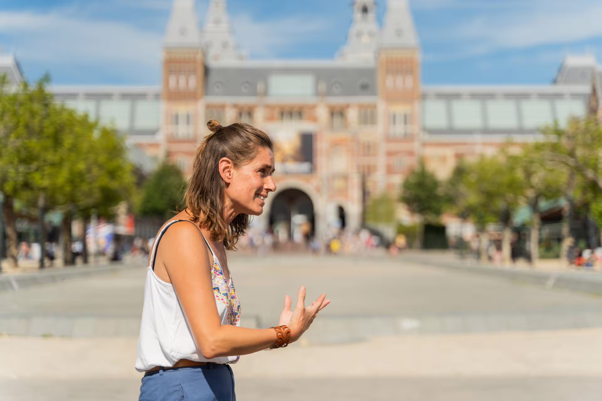Tour guide leading a small group bike tour in front of the iconic Rijksmuseum in Amsterdam on a sunny day.