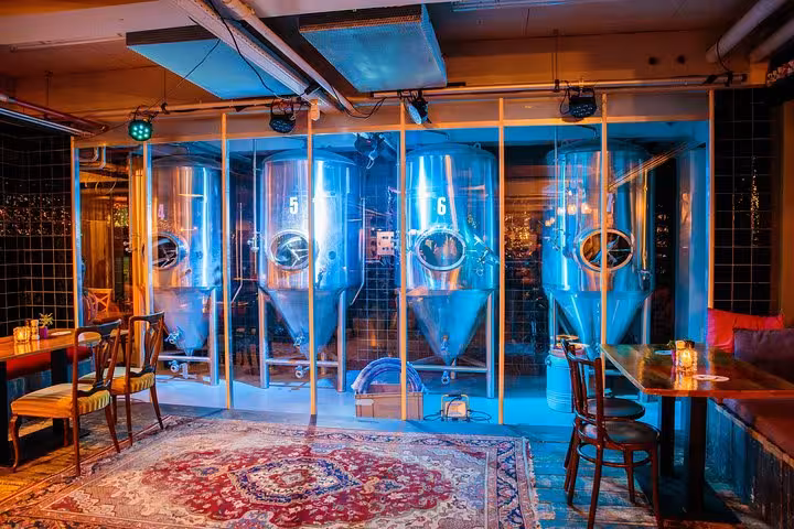 Modern Amsterdam brewery taproom with illuminated stainless fermenters, featured on craft beer bus tour
