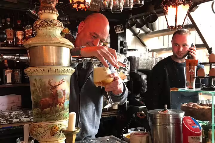 Bartender pouring beer in a cozy Amsterdam brown cafe, a local stop on Your Own Amsterdam random adventure tour