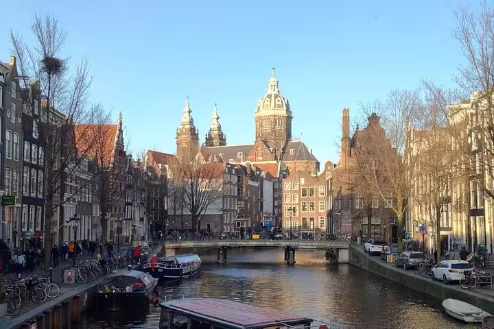 Amsterdam canal view with historic bridge and Basilica of St Nicholas on sightseeing tour with hidden gems and tastings