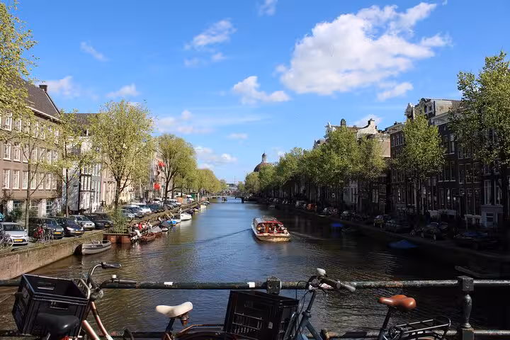 Amsterdam canal view from a bridge with bikes and tour boat, ideal for a private city walking tour with a local
