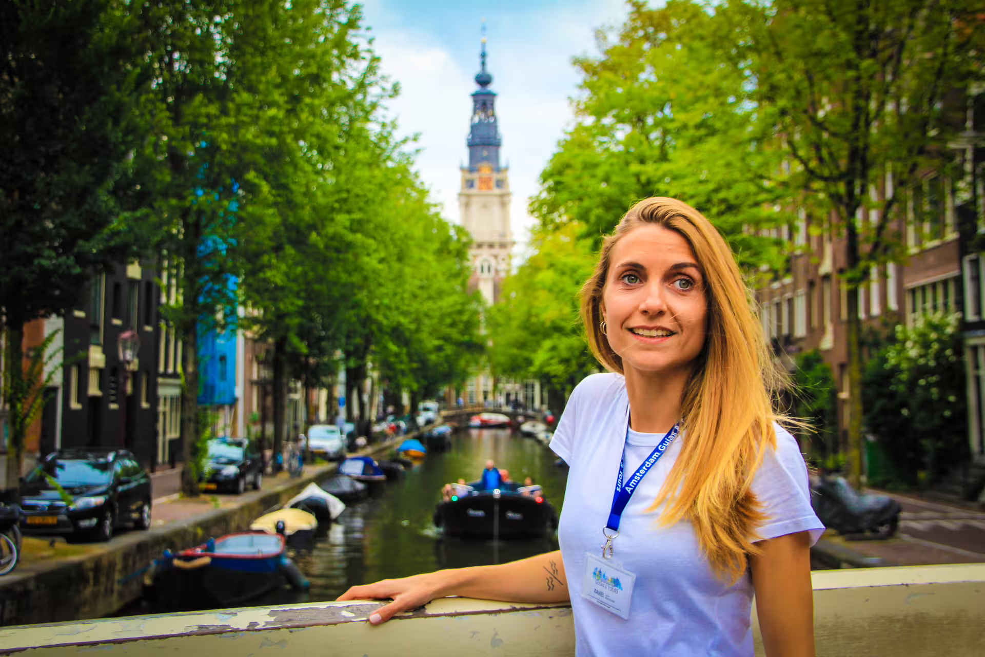 Tour guide on an Amsterdam canal bridge, showcasing scenic views and historic architecture during a small group walking tour.