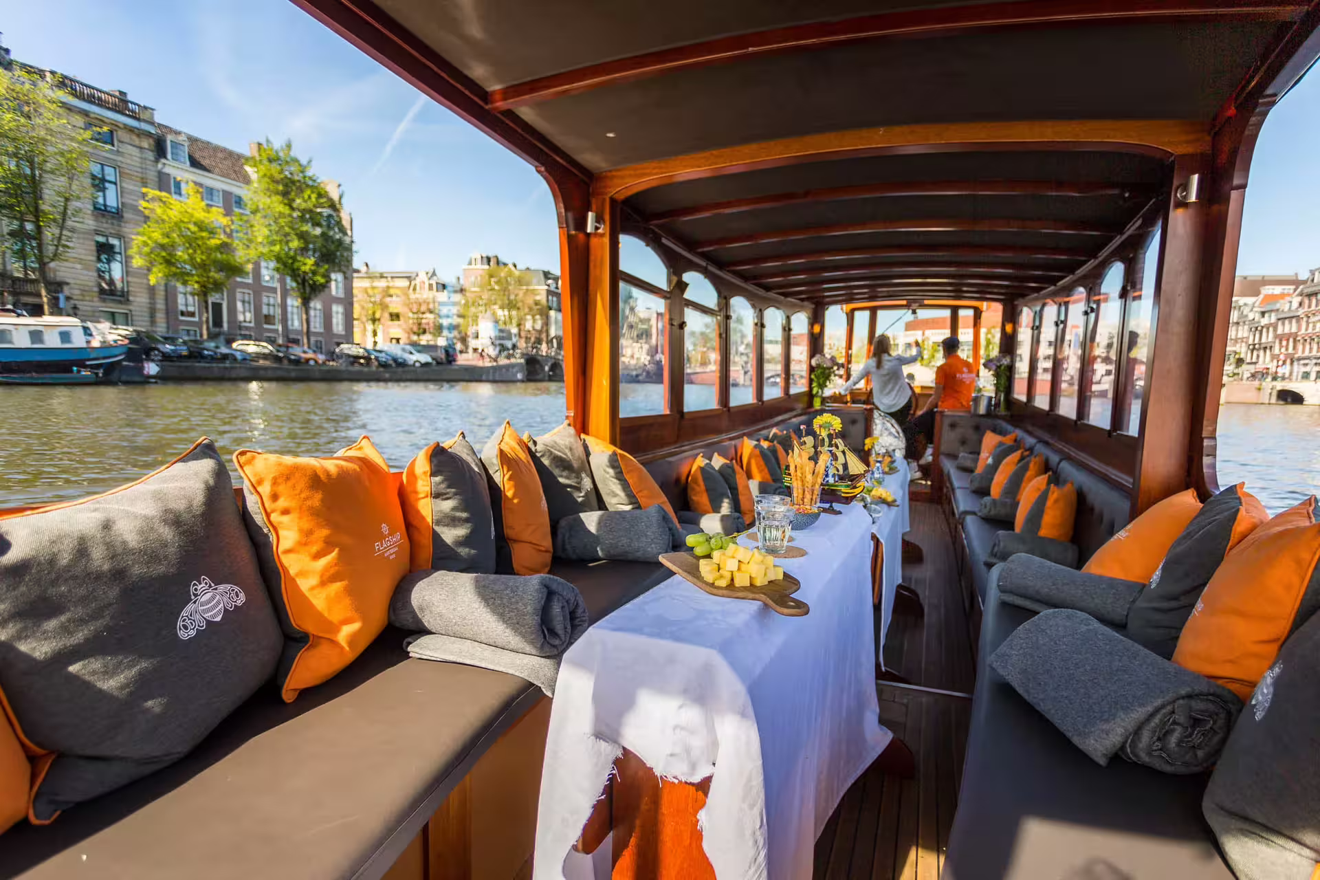 Luxurious Amsterdam canal cruise with cozy seating, cheese platter, and drinks, offering a scenic and relaxing experience.