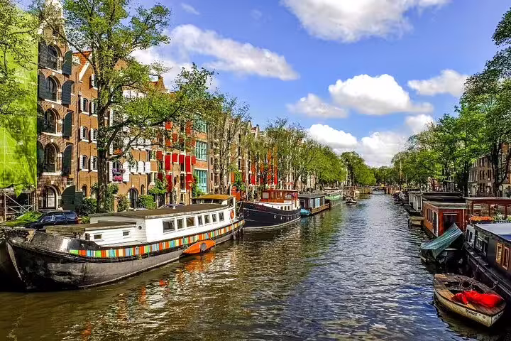 Amsterdam canal with houseboats and historic buildings, featured on Niki audio and GPS self-guided walk